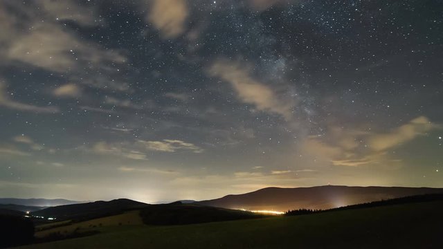 Stars sky with milky way galaxy and clouds moving over beautiful landscape time lapse