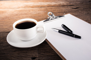 cup of coffee and clipboard with blank page and pen