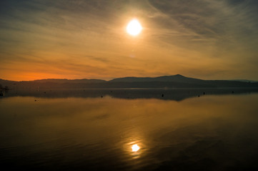 Naklejka premium Sunset on lake, with mountains and snow on background