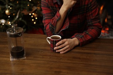 Coffee drinking flannel wearing male by fire during holidays/christmas