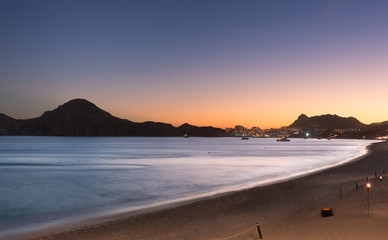 Fototapeta na wymiar Colorful, vivid sunset at beach with view of city and boats - Cabo San Lucas, Mexico