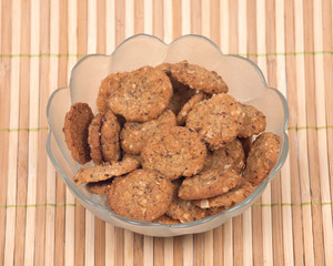 Crispy crunchy oatmeal raisin cookies in bowl on bamboo placemat