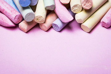Colored crayons on a pink background
