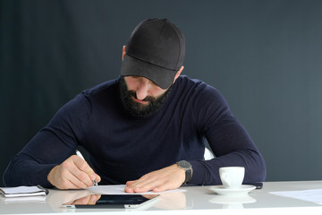 black beard Business man with black cap awriting text on his pap