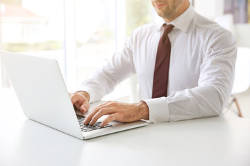 Male hands typing on laptop at office