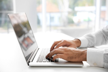 Male hands typing on laptop at office