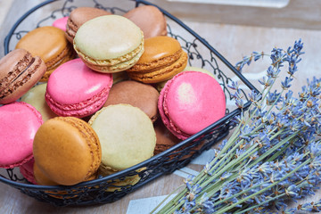 Colorful french macaroons in a heart shaped basket