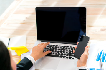 Closeup of business woman hand touch phone over laptop keyboard