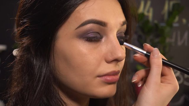 Makeup artist makes makeup for woman model