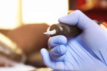 Male hand in glove holding tattoo machine, close up view