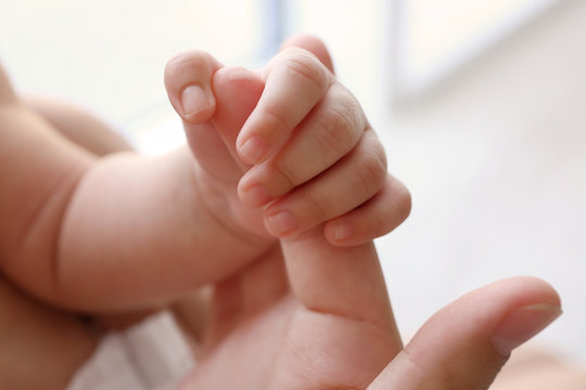 Close up view of cute baby hand holding mother finger