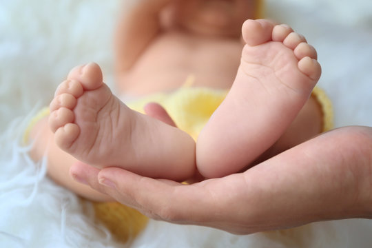 Woman hand holding bare baby feet, close up view