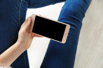 Woman holding modern cellphone at home