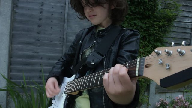 4k Shot of a Cute Child in Studio Playing his Guitar