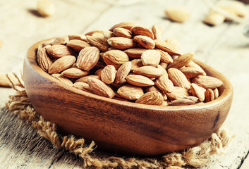 Raw peeled almond, vintage wooden background, selective focus