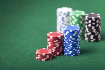 Stacked poker chips on green felt table. Shallow depth of field with focus on front stack.
