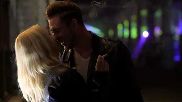 Young drunk couple kissing and smiling at party, people relaxing in night club