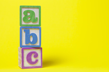 ABC Alphabet blocks stacked up on yellow background