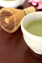 Matcha green tea on wood table with warm fall colors in soft-focus in the background. over light