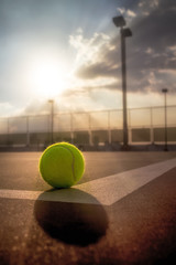 Tennis ball on hard court at sunset