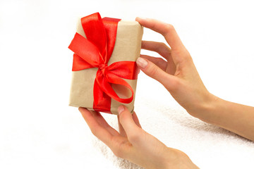 Beautiful caucasian female hands with gift box with red ribbon