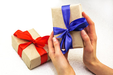 Beautiful caucasian female hands with gift boxes with red and bl