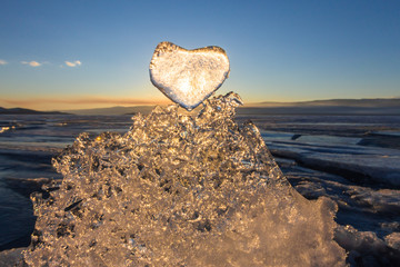Sun at sunset shines through the icy heart on texture transparen
