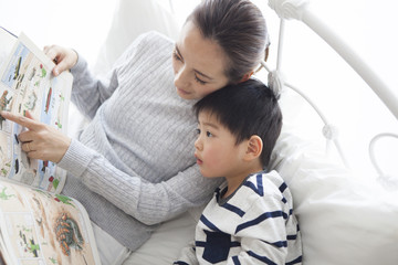 Mother and son are reading picture books in bed