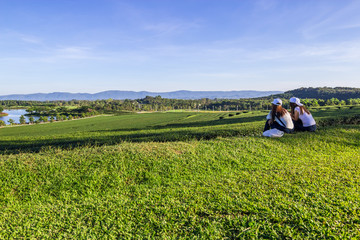 Fototapeta na wymiar Two girls with smartphone relaxing in the tea plantation with la