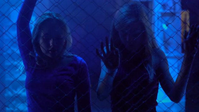 Pretty female go-go dancers moving to music in trance at nightclub, illumination