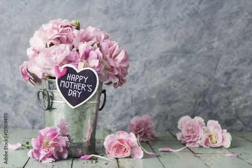 Pink carnation flowers in zinc bucket with happy mothers day let