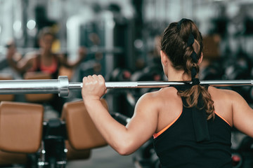 Woman in the gym . Woman exercising in gym with olympic barbell