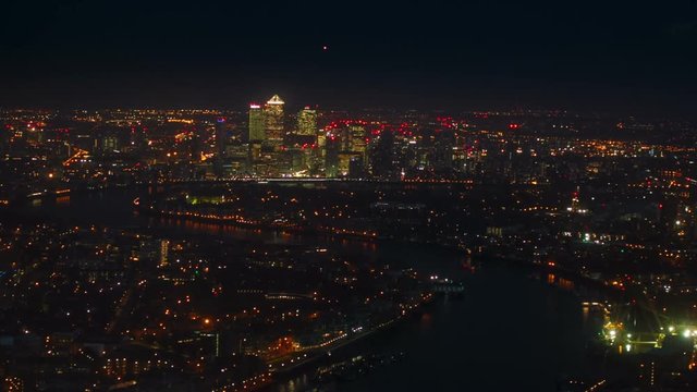 A night aerial shot of the illuminated Thames banks and Canary Wharf in London, England, UK seen from the tallest building in Europe