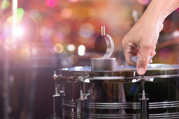 Hand adjusting tension rod of snare drum..Drummer measuring batter tension with drum dial and...