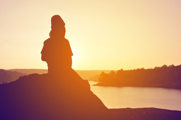 Silhouette of happy women on the rock near the river