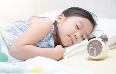 cute girl sleep on bed with alarm clock.