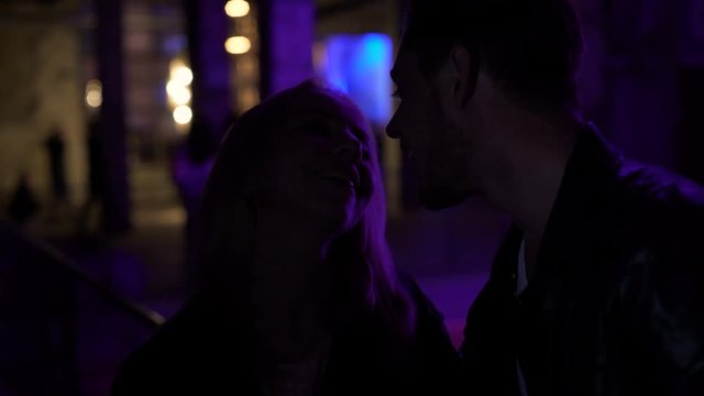 Young man flirting with blonde woman near night club, pick-up, relationship