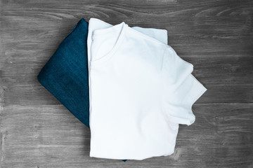 White T-shirt, denim jeans on a wooden board. Top view, Copy space.