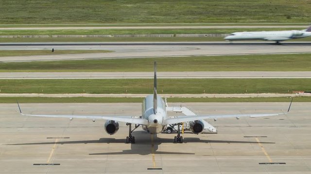 Commercial Airliner Action at a Hot Houston Bush Airport with a Regional Jet Landing on a Runway with a Parked Passenger Airplane in the Foreground