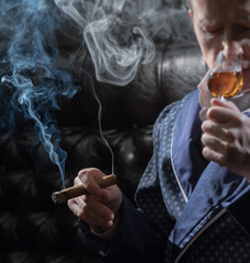 Man in an elegant robe smoking a cigar and drinking alcohol