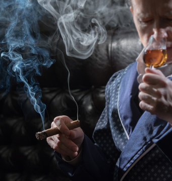 Man In An Elegant Robe Smoking A Cigar And Drinking Alcohol