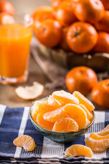 Tangerines, peeled tangerine and tangerine slices on a blue cloth. Mandarine juice.