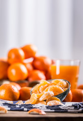 Tangerines, peeled tangerine and tangerine slices on a blue cloth. Mandarine juice.