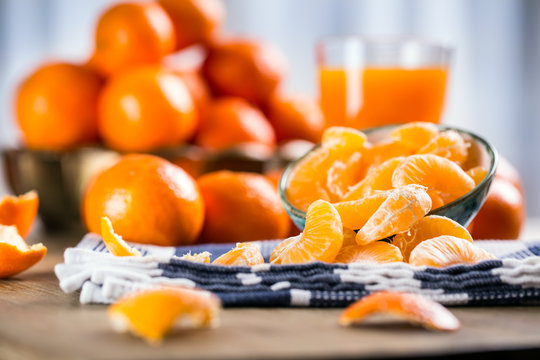 Tangerines, peeled tangerine and tangerine slices on a blue cloth. Mandarine juice.