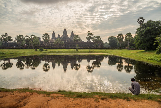 Cambodian people sitting near the pool in front of Angkor Wat the world heritage building of Siem Reap, Cambodia.