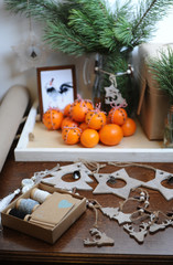 Obraz na płótnie Canvas Table with Christmas decor. Christmas tree branch in a glass. Gift wrapping with kraft paper. Tangerines with cloves