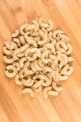 Brown rice elbow macaroni isolated on a wood background