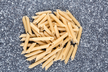 Brown rice penne on a mottled grey blue background