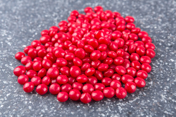 Red cinnamon candies on a mottled grey blue background