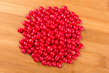 Red cinnamon candies isolated on a wood background